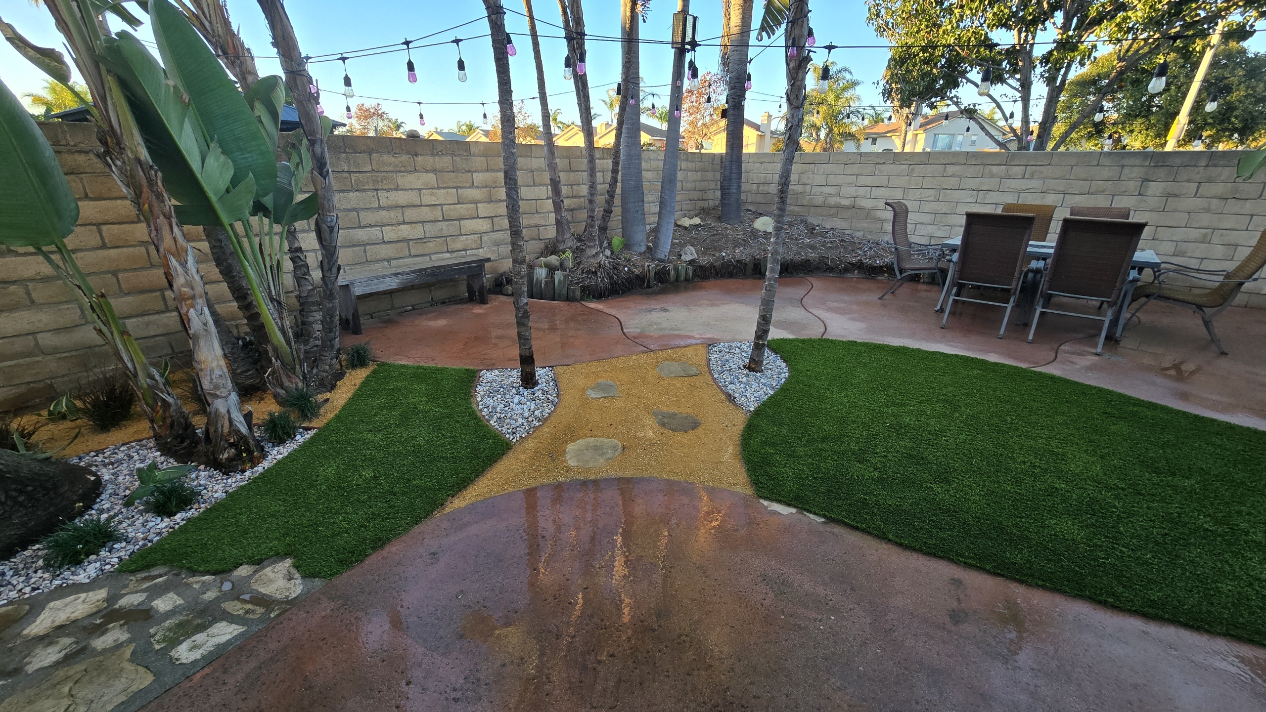Stained concrete patio with artificial turf and palm landscape design